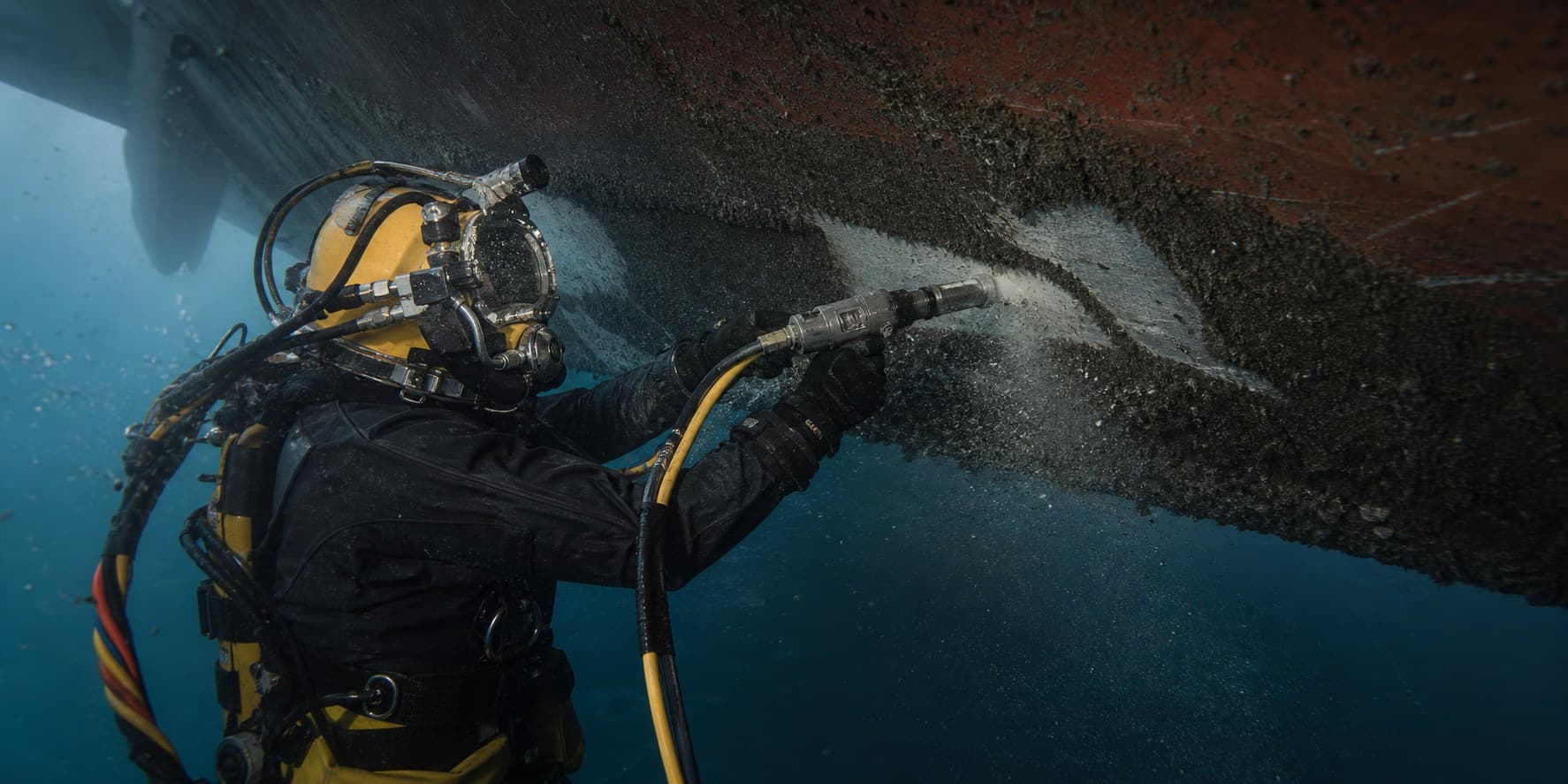 Commercial diver cleaning marine growth from a vessel hull